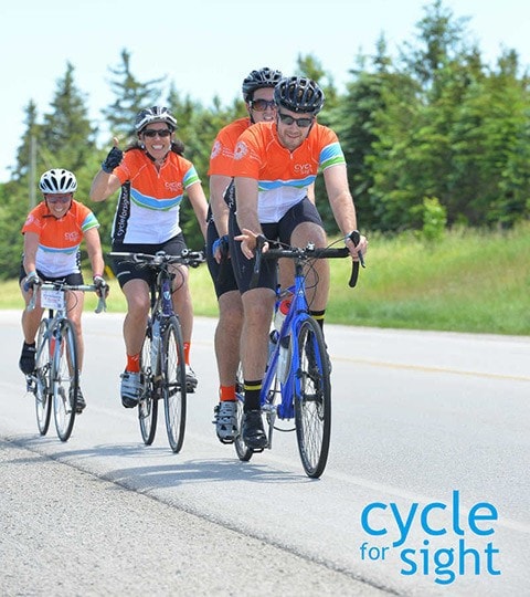 Quatre cyclistes souriants prennent part à la randonnée de collecte de fonds Cycle for Sight